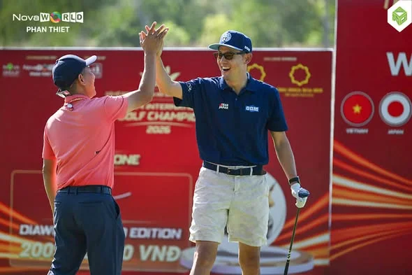 Hai golfer đập tay chúc mừng trước phông nền đỏ của một giải golf quốc tế