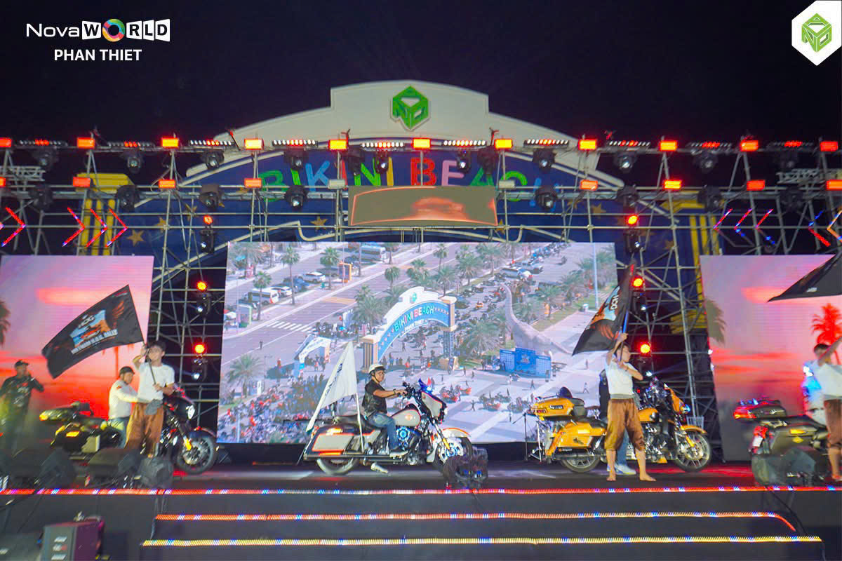 Sân khấu đêm Gala Vietnam H.O.G. Rally 2026 tại Quảng trường Bikini Beach, biker cầm cờ đứng cạnh mô tô Harley-Davidson trên sân khấu