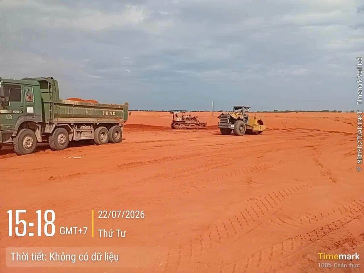 Xe ben đổ đất đắp, máy ủi san phẳng và lu đầm phía sau trên mặt bằng sân bay Phan Thiết