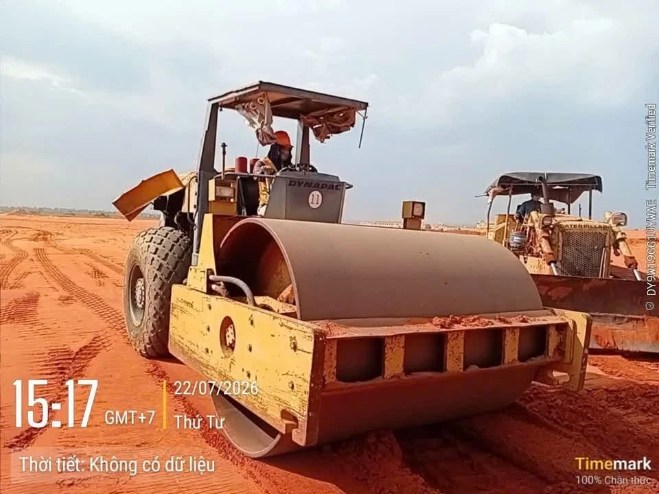 Lu bánh thép Dynapac đầm mặt lớp đất đắp, bên cạnh là máy ủi Caterpillar